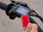 Digital display on a motorcycle handlebar with a red key fob held close to it.